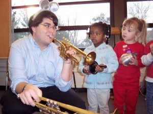 brass musician showing kids how to play